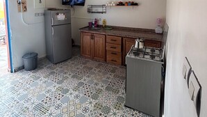 Eine kleine Küche mit Kühlschrank, Herd und Mikrowelle, einem Fernseher und Fliesen mit Muster.