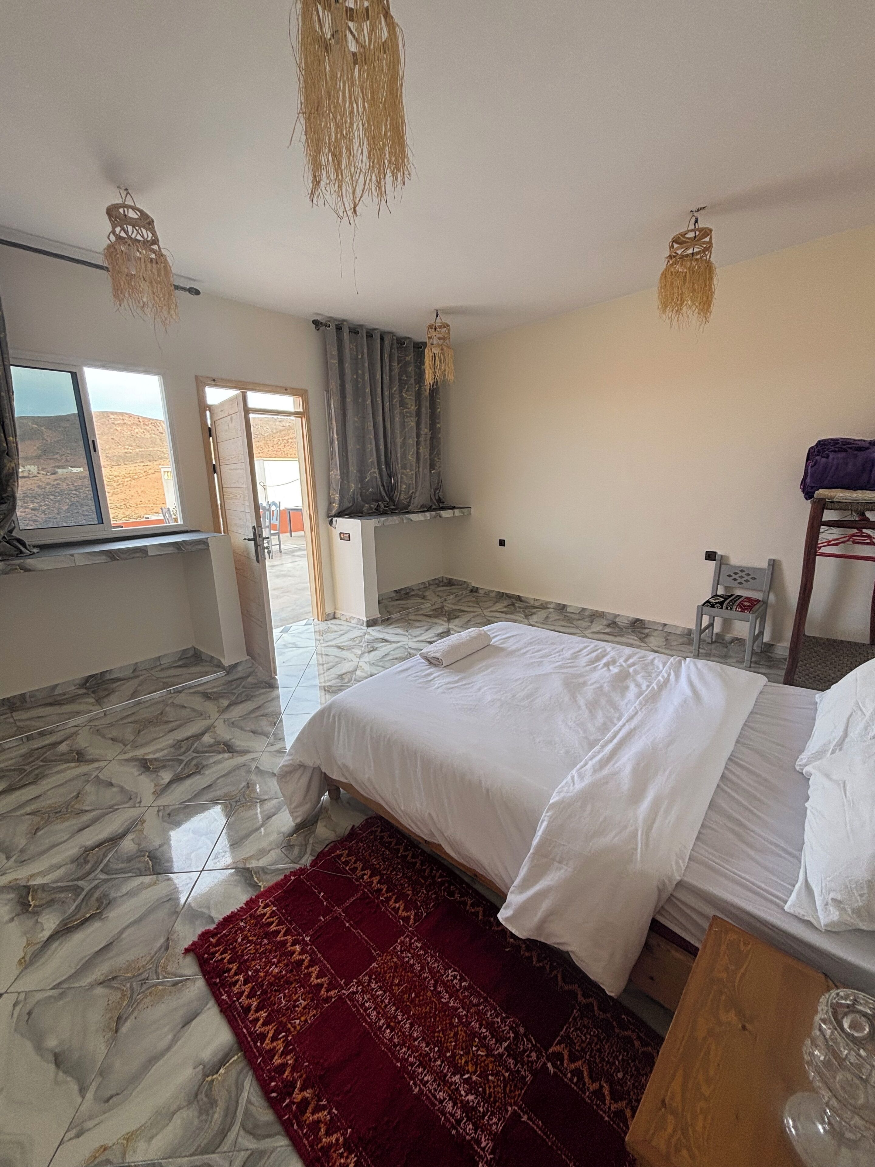 Un dormitorio con una cama, una alfombra roja, una mesita y una silla.