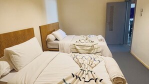 Ein Hotelzimmer mit zwei Betten, einem Holzkopfstück, einer Pendelleuchte und einer Tür zu einem weiteren Raum.