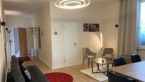 A modern living room with a sofa, chairs, a dining table, and a red rug. - Meeresbrise 1 Top location with garden use. Pet friendly! (Tönning)