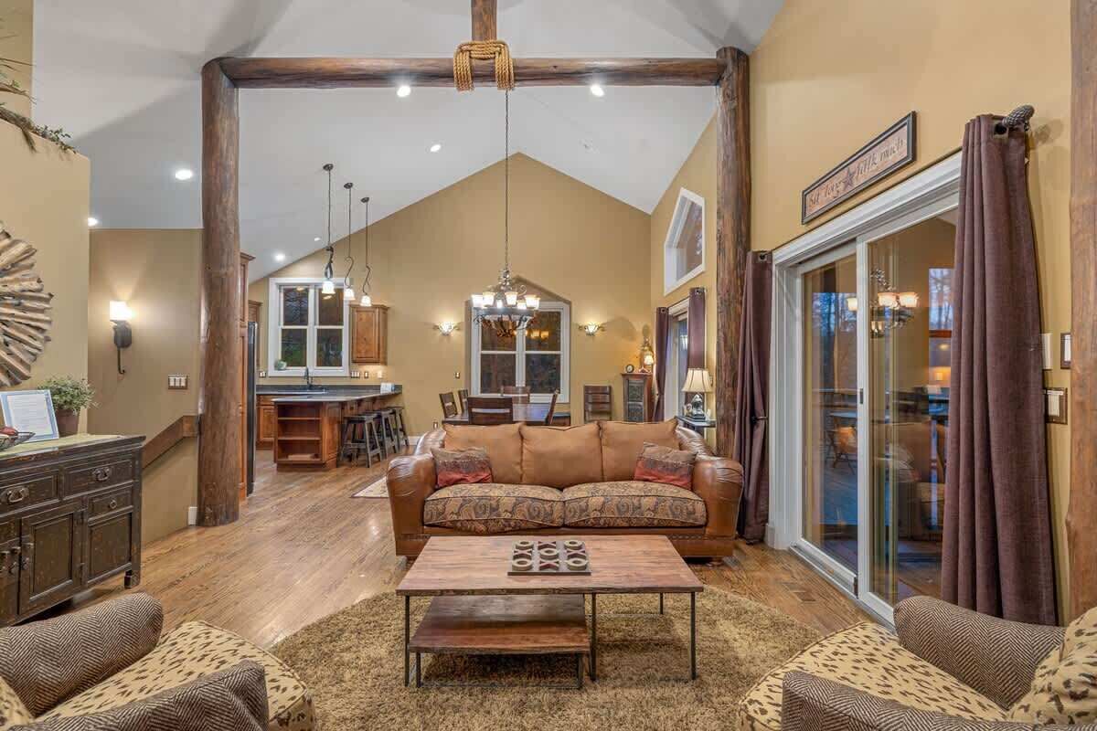 A spacious living room with a large sofa, a coffee table, and a dining area in the background.