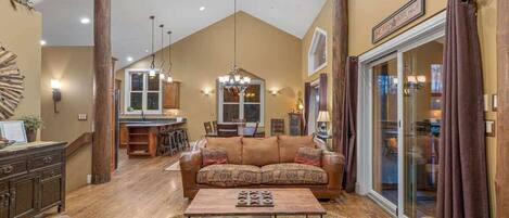 A spacious living room with a large sofa, a coffee table, and a dining area in the background.