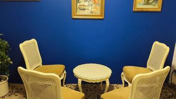 Guest rooms feature a vibrant wall, patterned carpet, and comfortable seating area with a small table and two chairs.