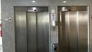 Two elevators with metallic doors and a fire extinguisher mounted on the wall.
