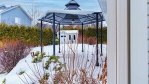 A gazebo with a snow-covered roof, surrounded by a garden with various plants and bushes. - Beautiful home for you (Sherbrooke)