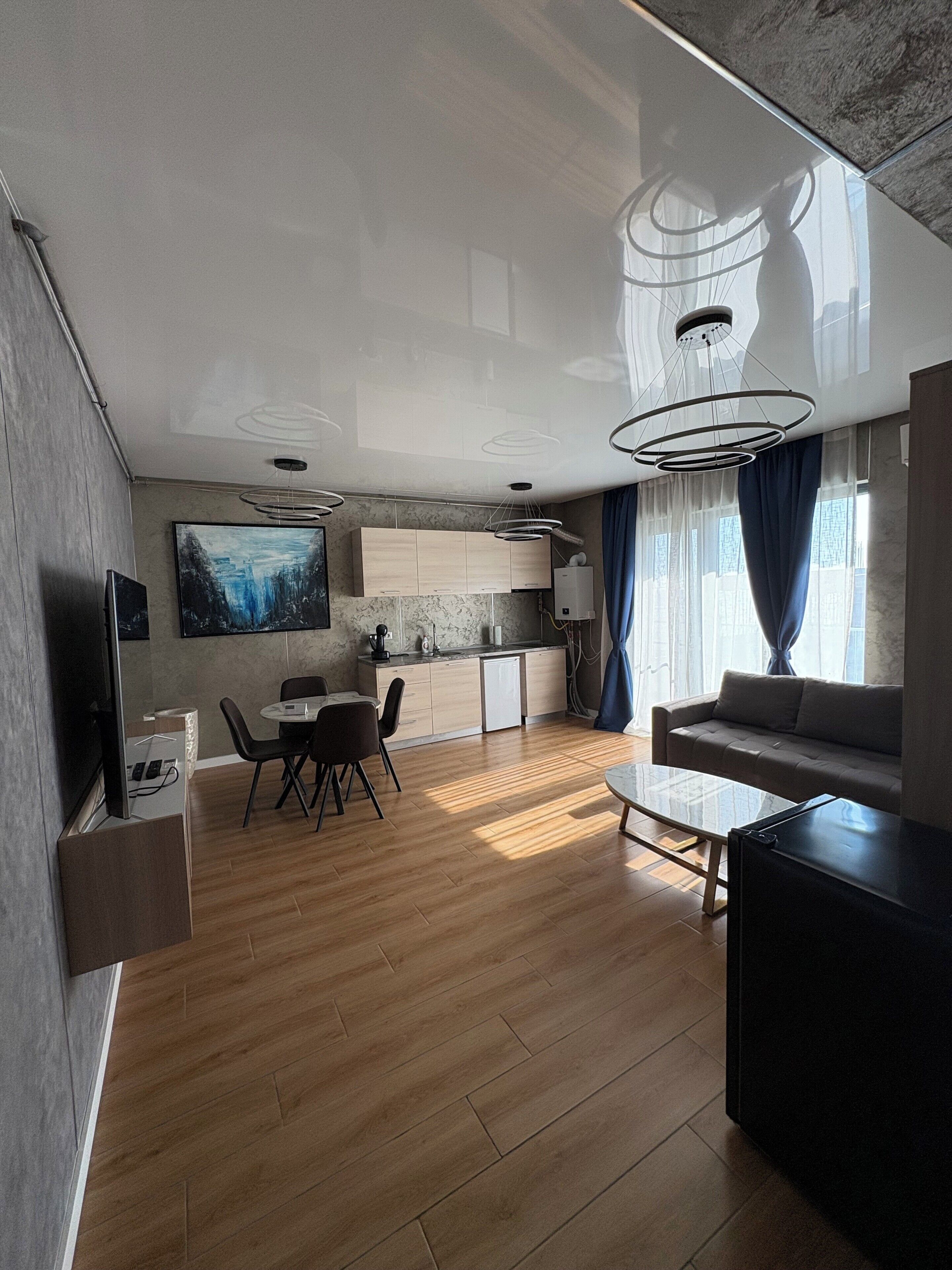 A modern living room with a sofa, a coffee table, and a dining area with chairs and a table.