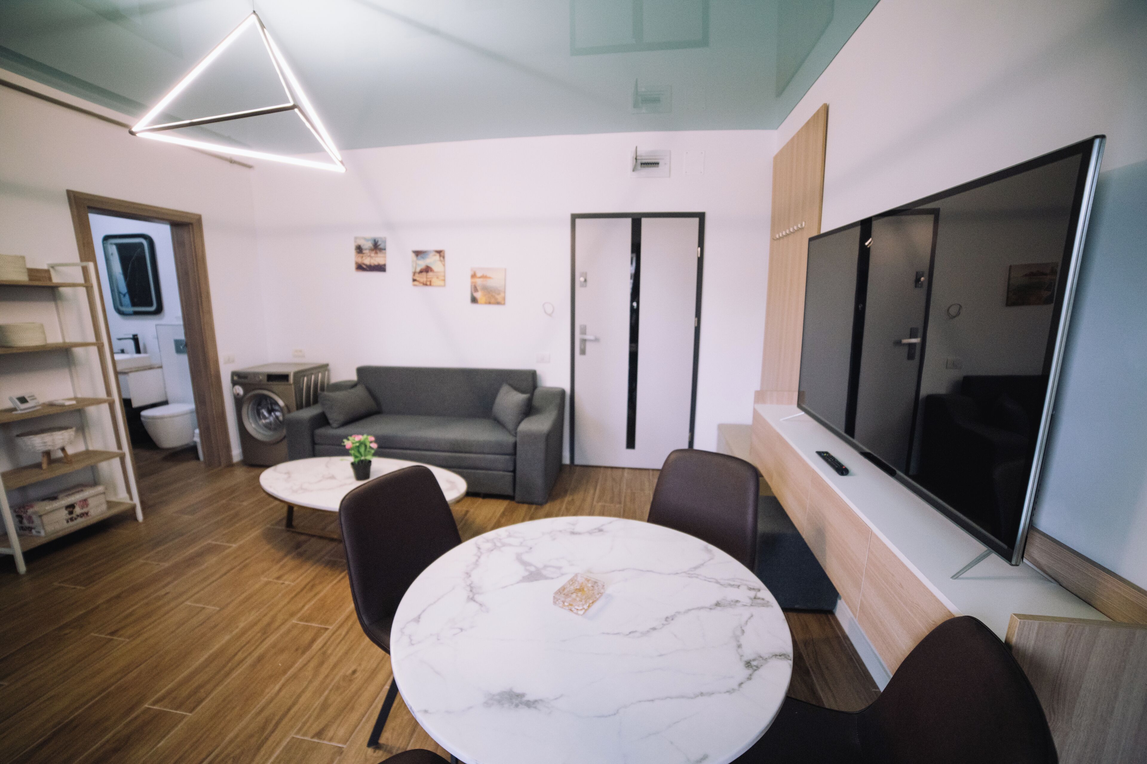 A modern living room with a sofa, a round table, and a TV.