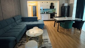 A modern living room with a sectional sofa, a round coffee table, and a dining area with a table and chairs. - Signature Promenada Hotel-Apartments 2 (Navodari)