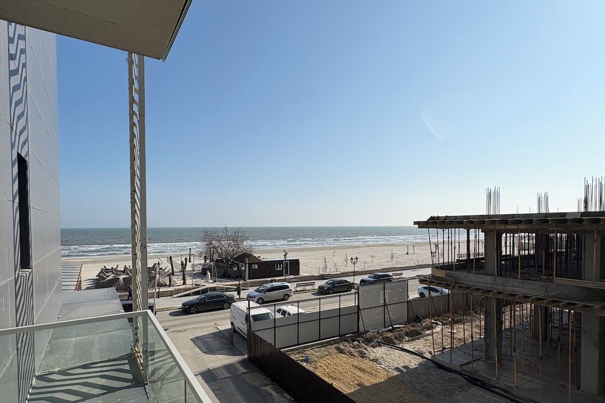 Une vue depuis un balcon donnant sur une plage, avec un ciel dégagé.