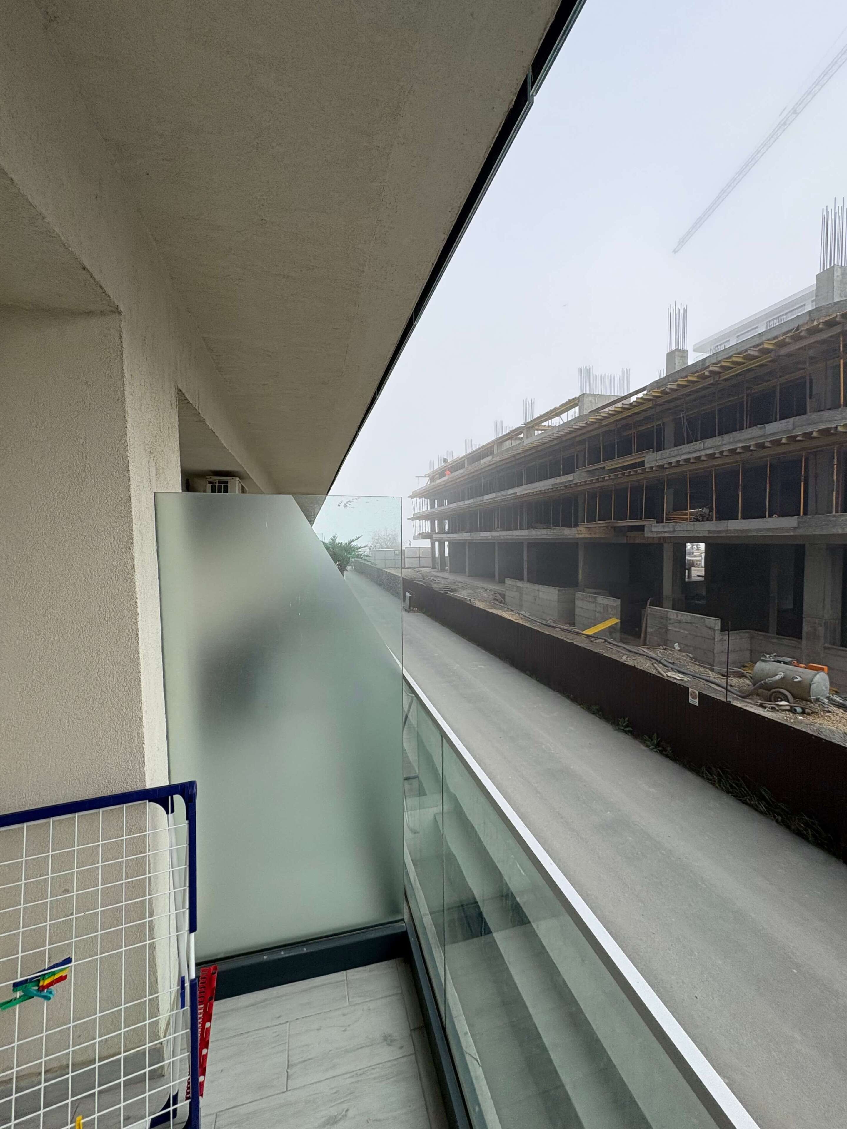 A view from a balcony overlooking a construction site with a building under construction.