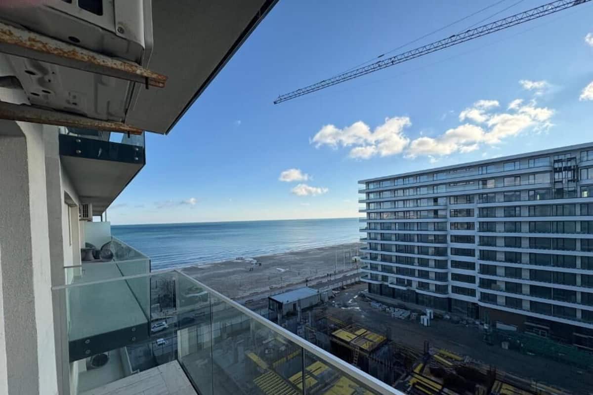 Un immeuble de grande hauteur offrant une vue sur l’océan et donnant sur un chantier de construction.