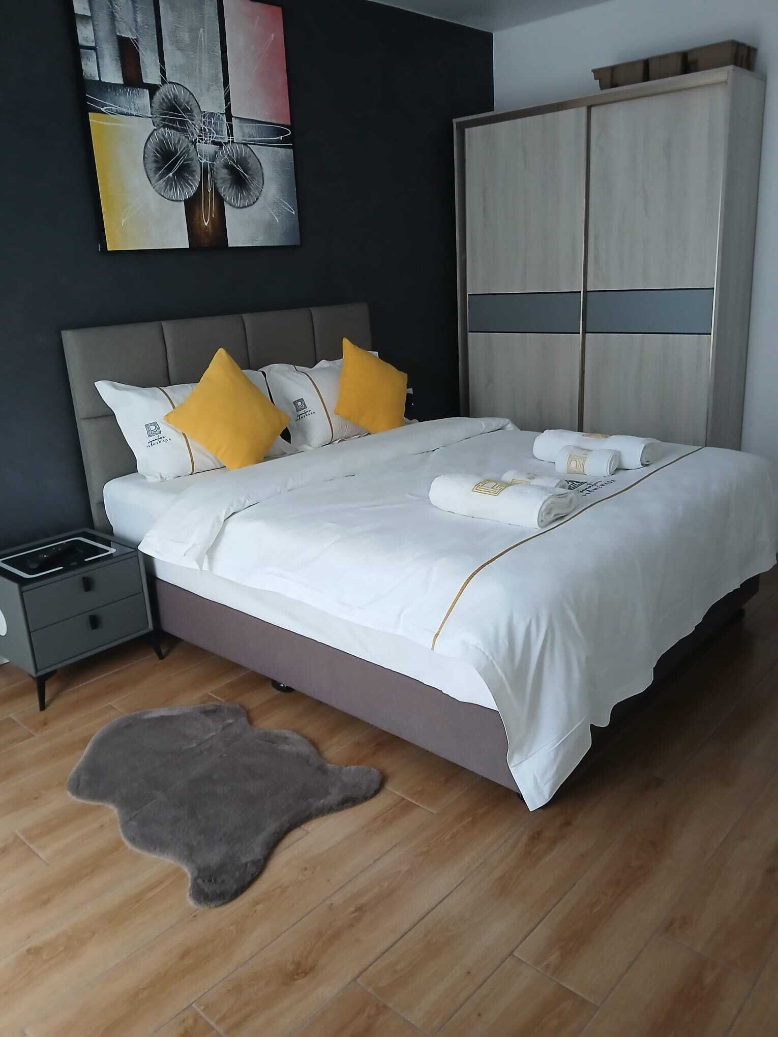 Un dormitorio moderno con cama, mesita de noche, armario y un cuadro en la pared.