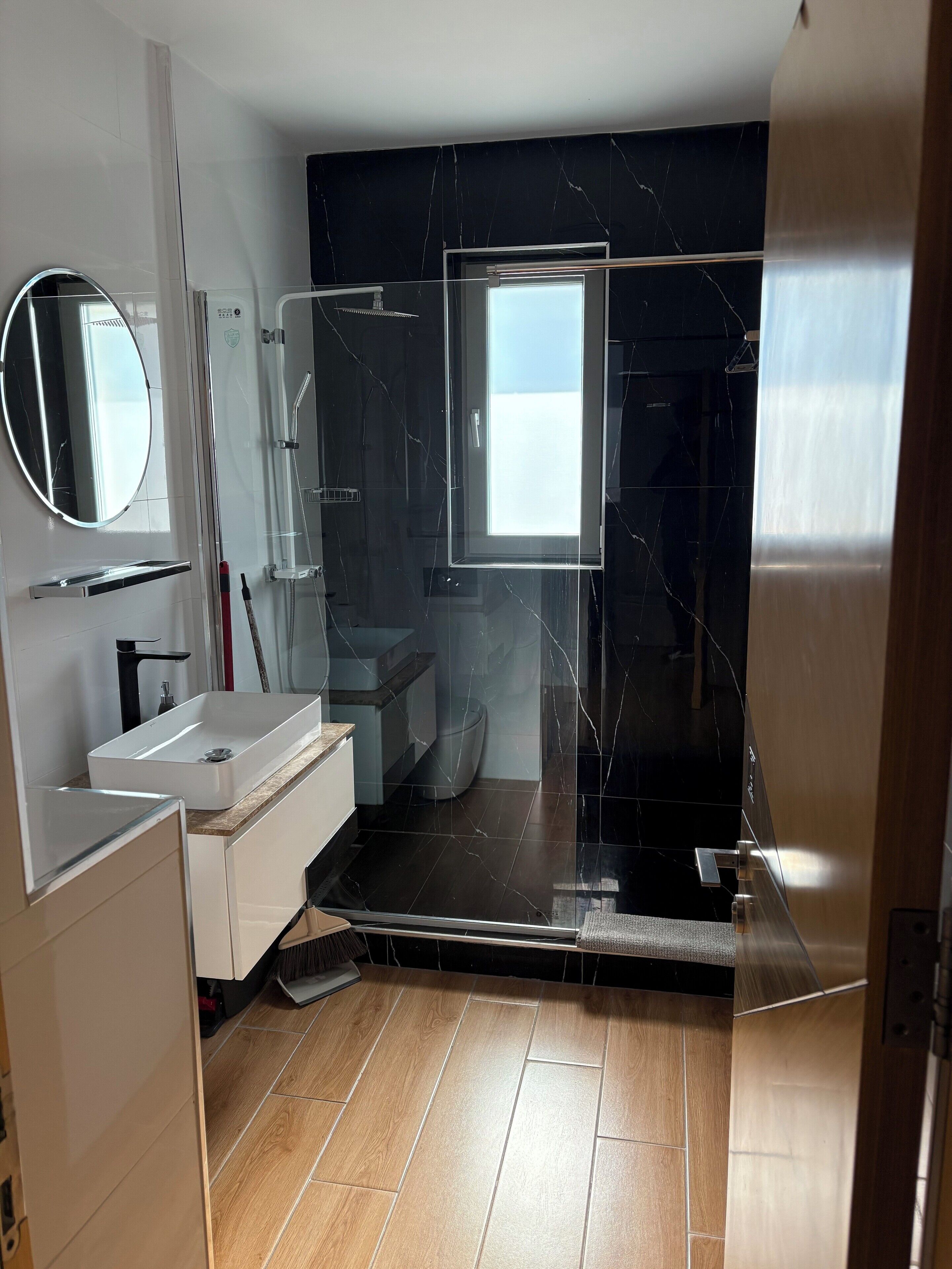 Un baño moderno con tocador, lavabo, espejo y cabina de ducha.