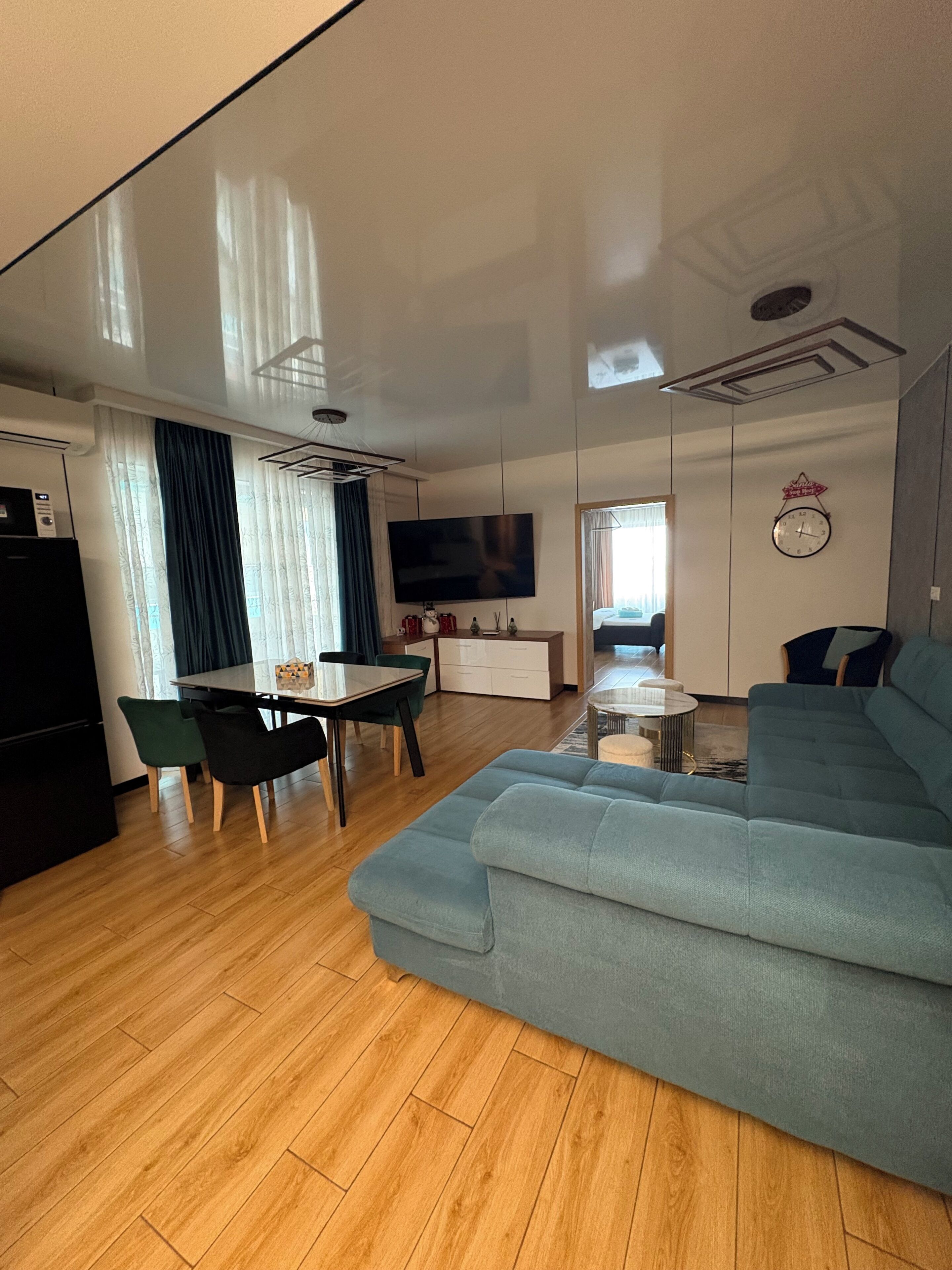 Una sala de estar moderna con sofá, mesa de comedor, sillas, televisor y una zona de cocina con microondas.