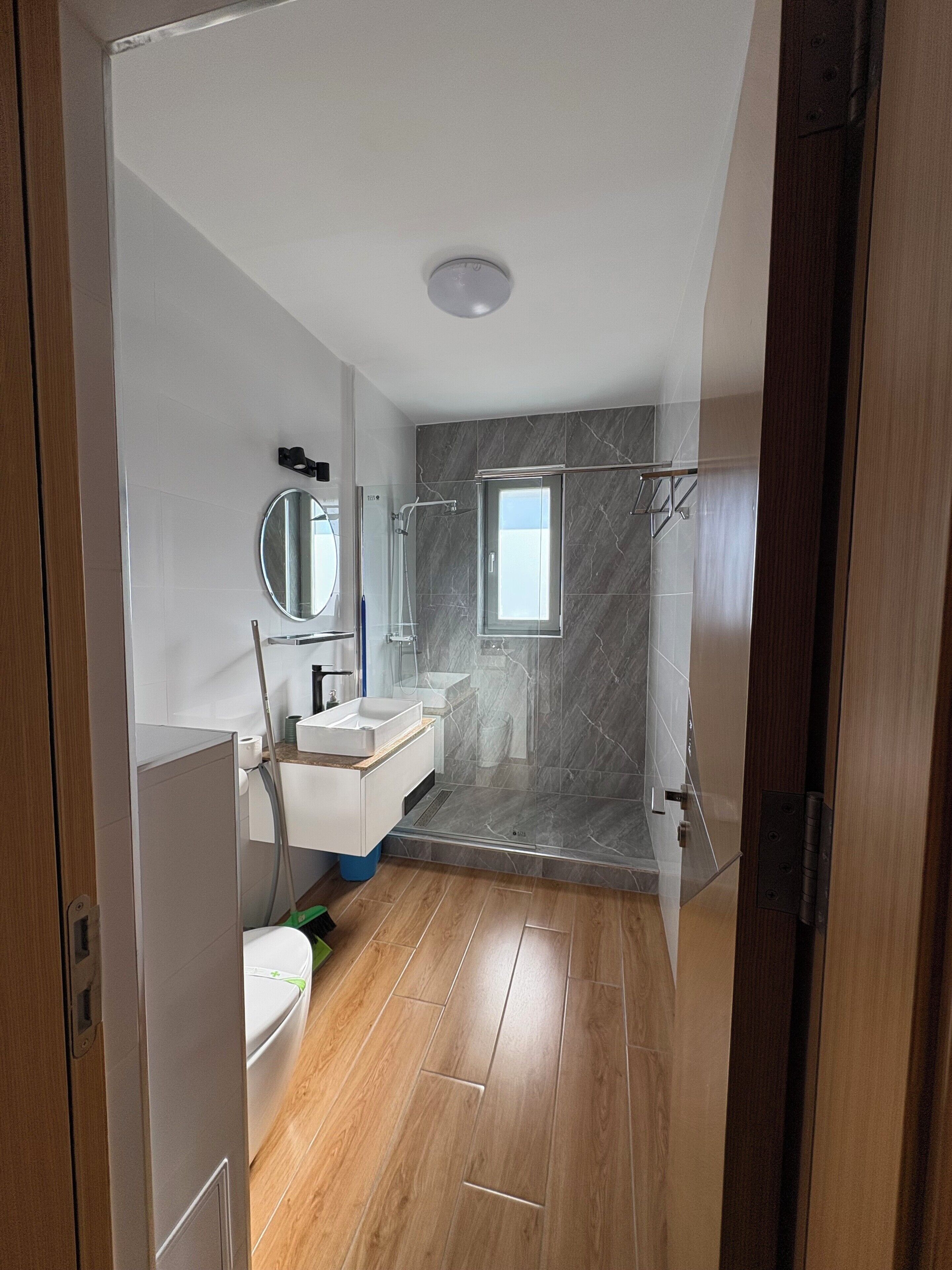 A modern bathroom with a shower, a sink, and a toilet.