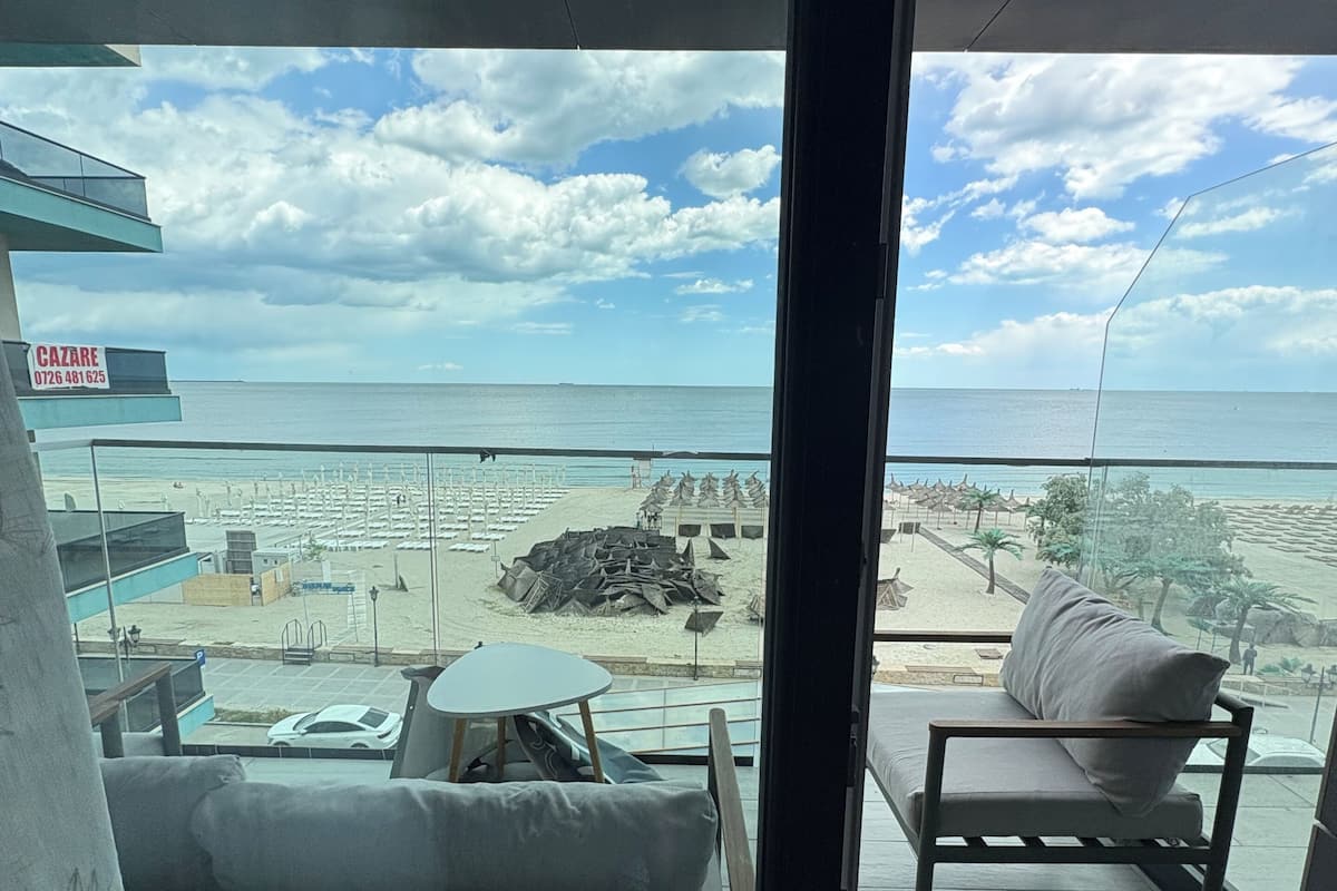 Un balcon avec vue sur la plage, un canapé, une table et un panneau indicateur.