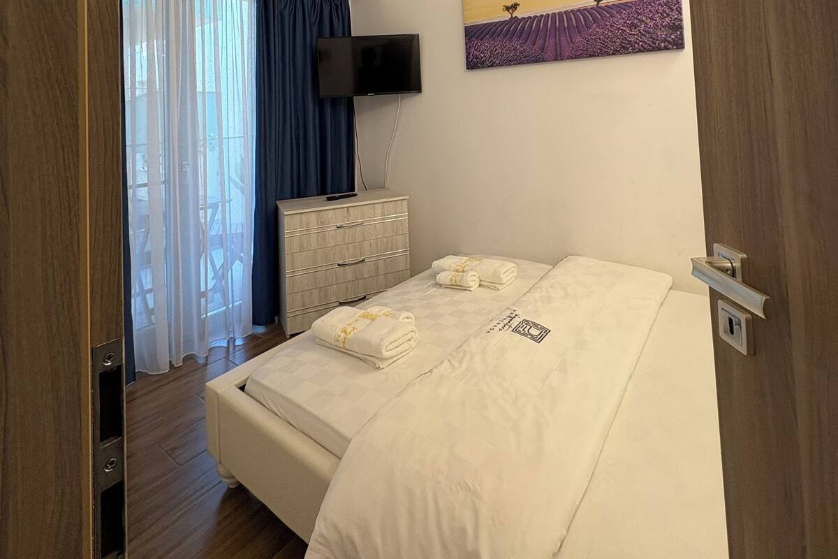 Une chambre d’hôtel avec un lit, une commode, un téléviseur et un tableau au mur.