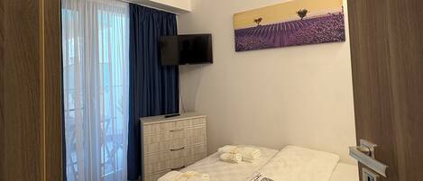 Une chambre d’hôtel avec un lit, une commode, un téléviseur et un tableau au mur.