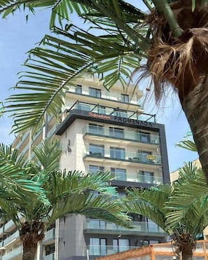 Un hôtel à plusieurs étages, nommé « Signature PROMENA », doté de balcons et présentant un design architectural moderne.