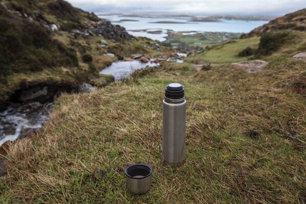A stainless steel water bottle and a cup on a grassy hill overlooking a body of water and rocky terrain. - Comfy Annexe near Croagh Patrick with sea views
(Murrisk)