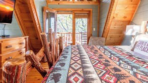 Un dormitorio de cabaña con una cama, un tocador de madera y un televisor sobre el tocador.