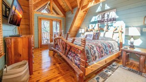 Un dormitorio de cabaña acogedor con una cama, muebles de madera y un televisor en la pared.