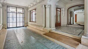 En imponerande entré med en stor glasdörr, ett marmorgolv och klassiska arkitektoniska detaljer.