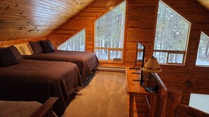 Ein gemütliches Schlafzimmer in einer Hütte mit zwei Betten, einem Schreibtisch und großen Fenstern mit Blick auf den Wald.