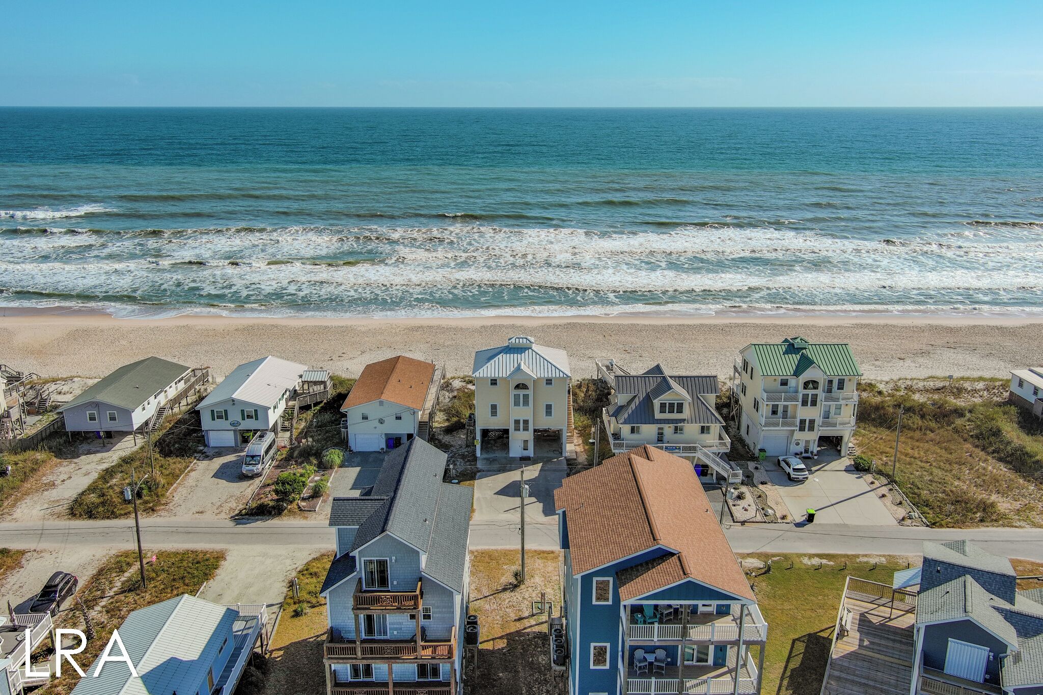 Un área residencial costera con casas cerca de la playa, que presenta una mezcla de estilos arquitectónicos y una vista despejada del océano.