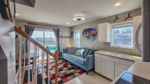 A modern kitchen with white cabinets, a blue sofa, and a colorful rug. - Buccaneers Bounty II: Enjoy Stunning Ocean Views (North Topsail Beach)