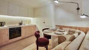 Eine moderne Küche mit Einbauofen, einem Esstisch für vier Personen und einer gemütlichen Sitzecke mit Sofa und Sesseln.