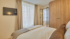Ein modernes Schlafzimmer mit einem großen Bett, einem flachbildfernseher an der Wand und einem Holzschrank.