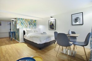 A modern hotel room with a bed, a desk with chairs, a small table, and a wall with a geometric pattern. - Sublime and new Apartment Le Marais / Beaubourg (Paris)