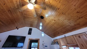 Une cuisine avec un plafond en bois, un ventilateur de plafond, une fenêtre, un réfrigérateur et un four à micro-ondes.
