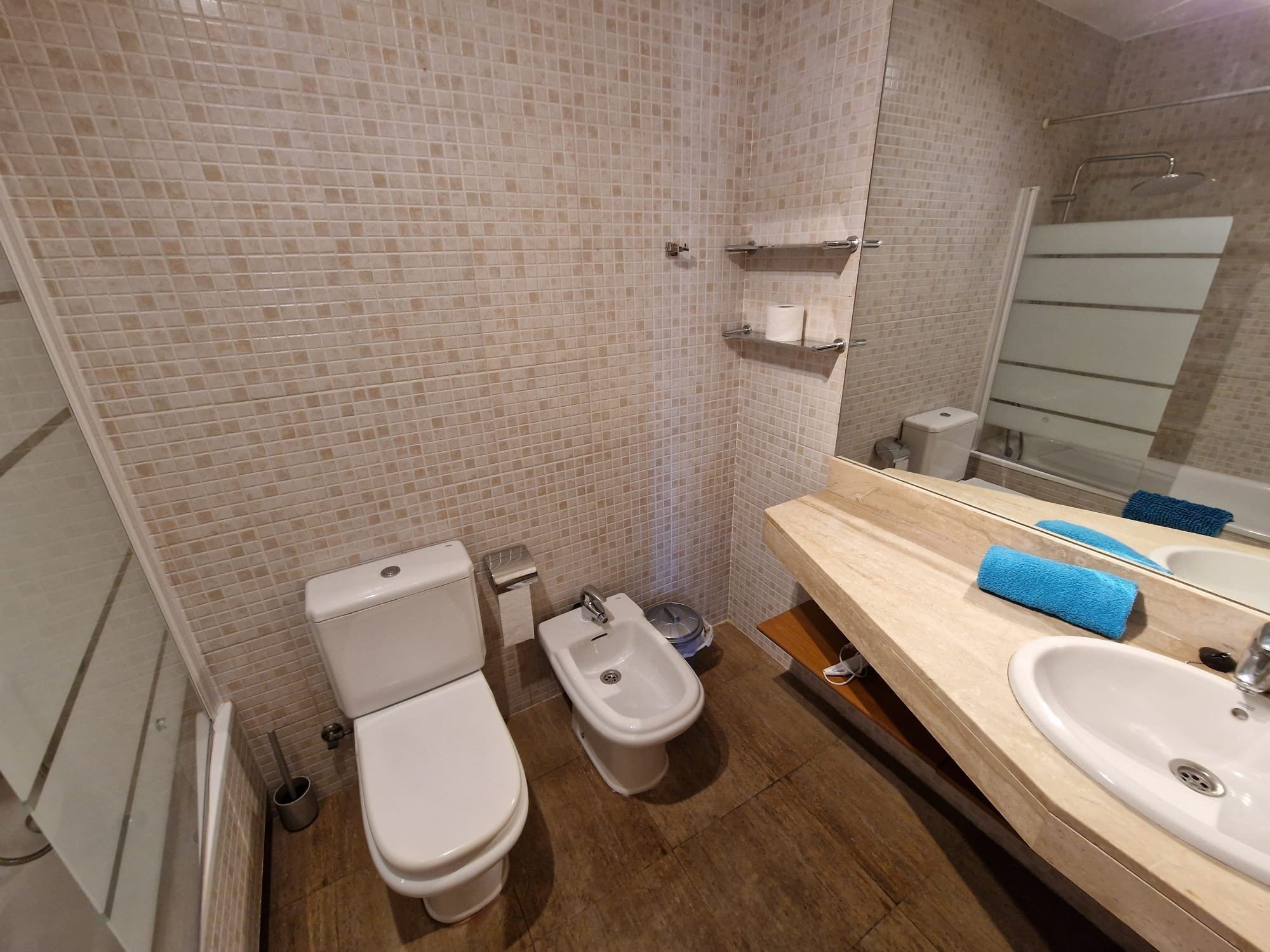 A bathroom with two toilets, a bidet, a sink, and a mirror.
