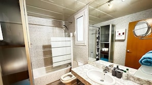 A modern bathroom with a glass shower enclosure, a toilet, a sink with a marble countertop, and a large mirror. - Rooms Aribau 133 (Barcelona)