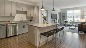 Cocina moderna con una isla central, taburetes de bar y un área de comedor con sofá y mesa de centro.