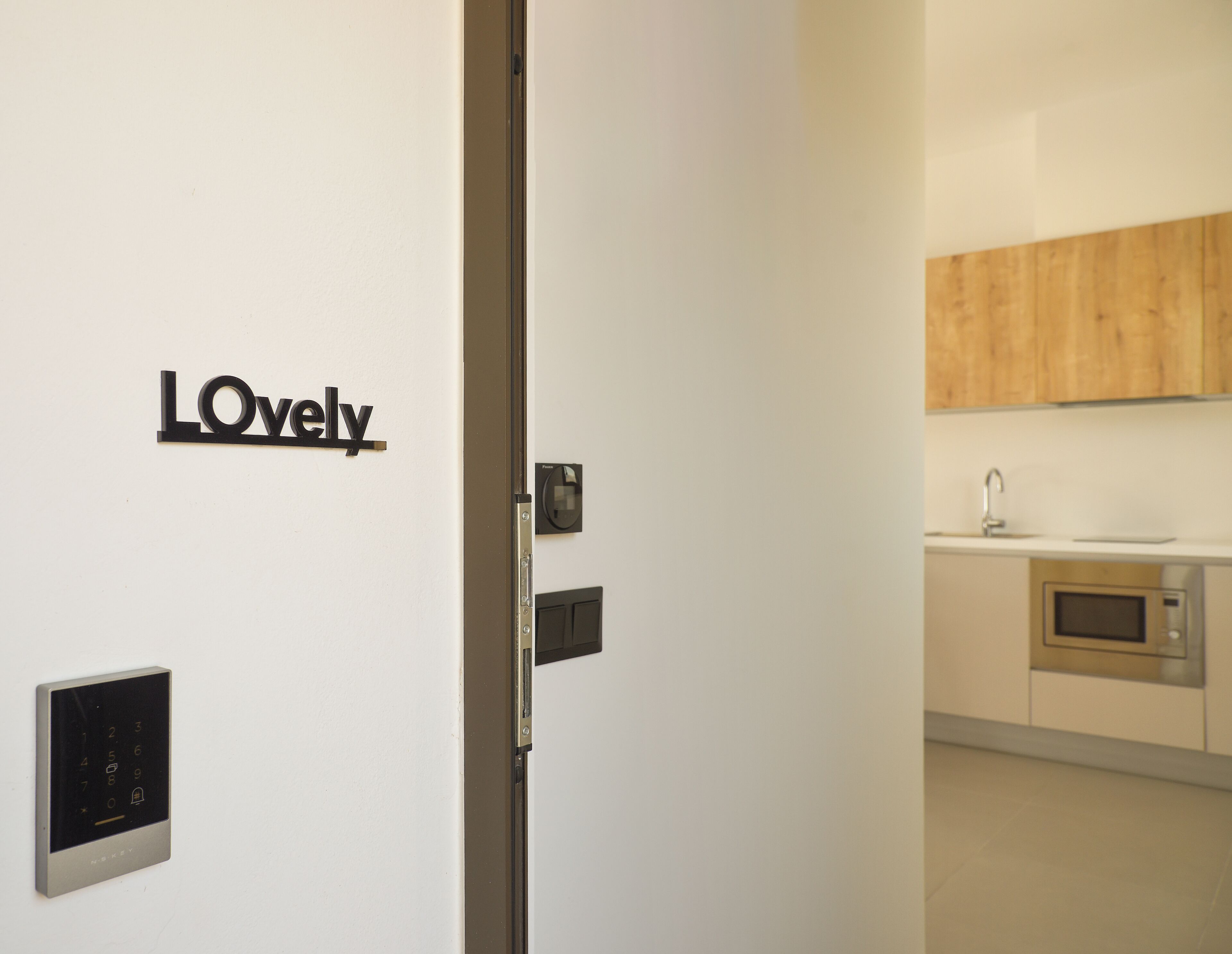 A modern kitchen with a wooden cabinet above the sink and a wall-mounted digital lock.