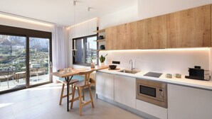 Une cuisine moderne dotée d’un grand îlot central, d’appareils électroménagers en acier inoxydable et offrant une vue sur le paysage urbain grâce à de grandes fenêtres.