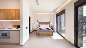 Une chambre moderne avec un grand lit, une table de chevet, une armoire intégrée et une vue sur l’extérieur grâce à une porte-fenêtre coulissante.