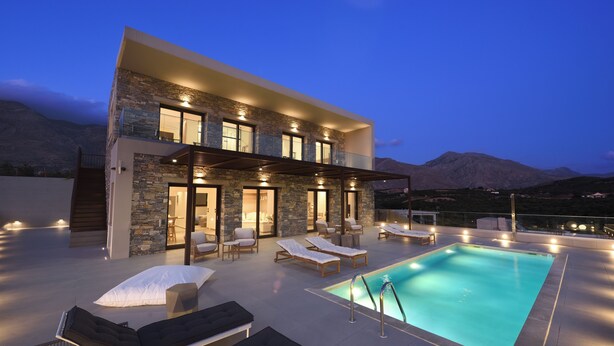 Une maison moderne dotée d’une piscine, d’un espace salon extérieur et offrant une vue sur les montagnes.