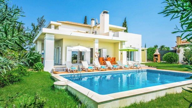 Ein modernes Haus mit Schwimmbad, Sitzgelegenheit im Freien und üppigem Grün.