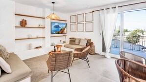 A modern living room with a sofa, wicker chairs, a coffee table, and a large window with a city view. - Brisa y Mar - Six Bedroom Villa, Sleeps 12 (Calp)