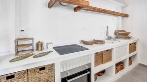 A modern kitchen with white cabinetry, wooden beams, a black countertop, and wicker baskets. - Brisa y Mar - Six Bedroom Villa, Sleeps 12 (Calp)