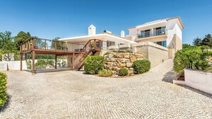 A modern house with a stone staircase, a wooden deck, and a stone wall.