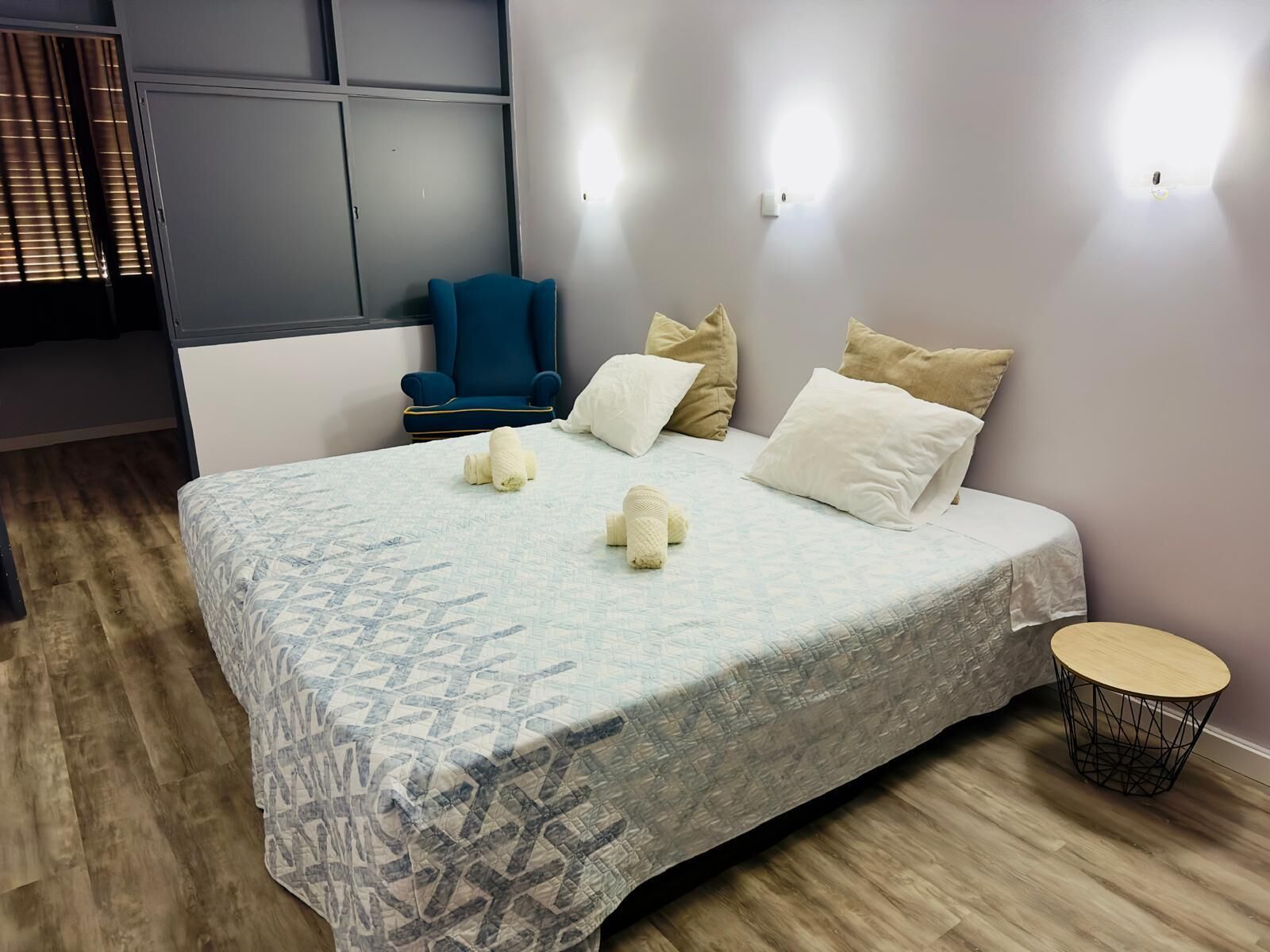 Habitación de hotel ordenada con una cama grande, una silla y una mesita redonda.