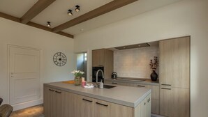 A modern kitchen with wooden cabinets, a central island, and a clock on the wall.