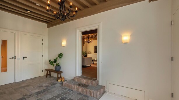 A spacious foyer with a stone floor, a bench, a potted plant, and a staircase leading to another room.
