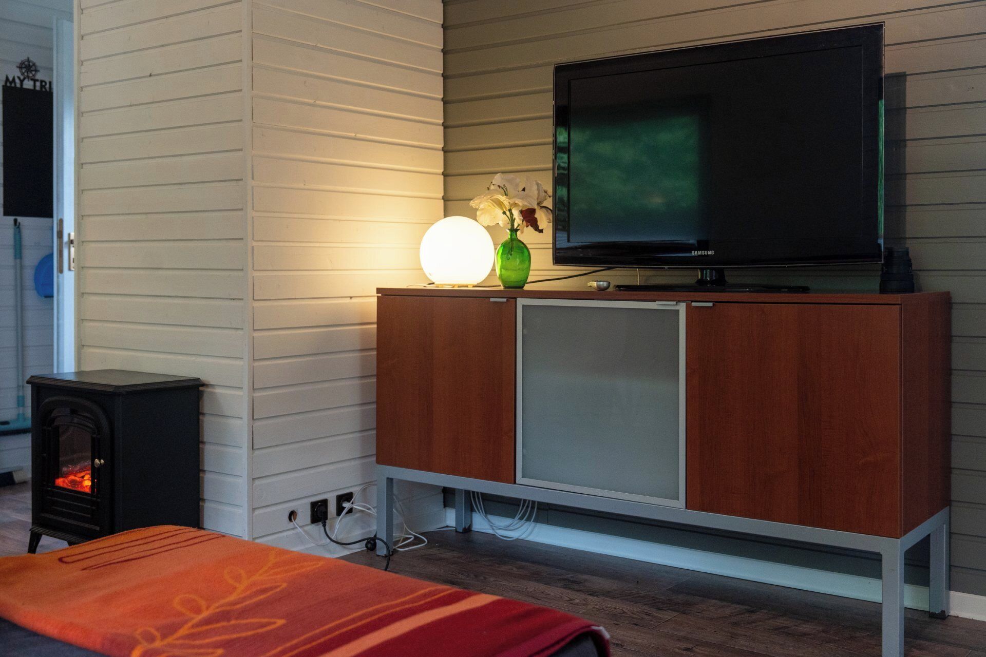 Ein modernes Wohnzimmer mit Fernseher auf einem Holzschrank, Kamin und einem gemütlichen Teppich.