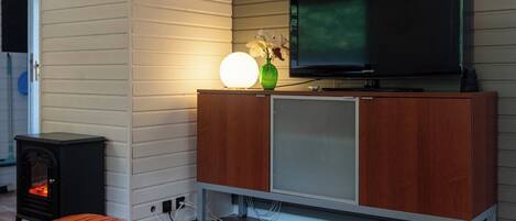 Ein modernes Wohnzimmer mit Fernseher auf einem Holzschrank, Kamin und einem gemütlichen Teppich.